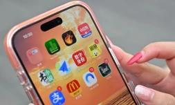 Une utilisatrice de Xiaohongshu se prépare à ouvrir l'application chinoise (en haut à droite) alors qu'elle visite la Cité interdite à Pékin, le 11 juillet 2026