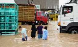 Des habitants de la ville de Baao marchent les rues inondées après le passage de la tempête Usman, le 30 décembre 2018