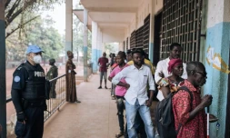 Des électeurs font la queue devant un bureau de vote de Bangui, sous l'oeil d'un policier de la Minusca, le 27 décembre 2020