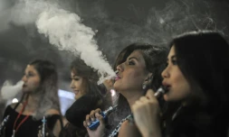 Des personnes fument des cigarettes électroniques pendant la VapeFair à Kuala Lumpur, le 5 décembre 2015