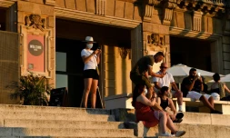 Des visiteurs assis devant le musée national d'art de Barcelone le 25 juillet 2020