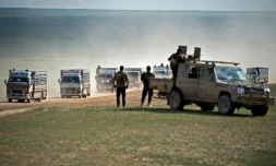Des combattants des Forces démocratiques syriennes (FDS) surveillent un convoi de civils fuyant le dernier réduit du groupe jihadiste Etat islamique dans l'est de la Syrie, le 11 février 2019 