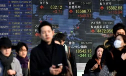 Des piétons passent devant un tableau indiquant les cours de la bourse, à Tokyo le 22 janvier 2016