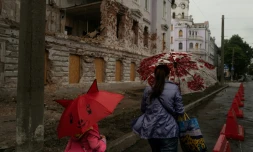 Une mère et sa fille passent près d'un bâtiment détruit par un bombardement russe, le 12 juin 2025 à Soumy, dans le nord-est de l'Ukraine 