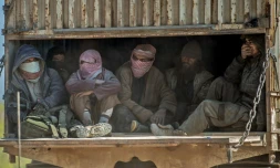 Des combattants présumés du groupe Etat islamique qui se seraient rendus aux Forces démocratiques syriennes (FDS) sont évacués en camion de Baghouz dans la province de Deir Ezzor (nord-est), le 20 février 2019 
