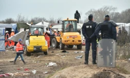 Des policiers surveillent le démantÚlement d'abris dans la "jungle" de Calais par des bulldozers, le 1er mars 2016