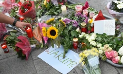 Bougies, fleurs et note où est inscrit "Pourquoi" rendent hommage aux neuf victimes du forcené, à l'entrée du centre commercial de Munich le 23 juillet 2016