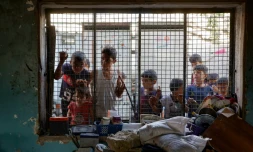 Des enfants palestiniens regardent depuis le grillage d'une salle de classe endommagée de l'école al-Farabi transformée en abri pour déplacés, après avoir été touchée par une frappe israélienne dans la ville de Gaza, le 7 septembre 2025