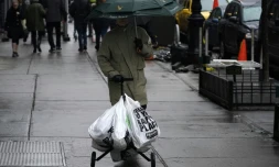 Un homme marche avec un chariot de sacs en plastique contenant ses courses le 28 février 2020 à Manhattan
