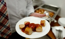 Un employé du constructeur automobile allemand Volkswagen tente une assiette de currywurst (saucisse au curry), au siège de l'entreprise à Wolfsburg en Allemagne le 21 avril 2016