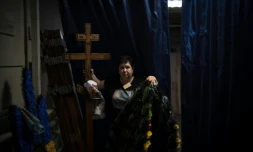 Svitlana Ostapenko, gérante du funérarium de Sumy, dans le nord-est de l'Ukraine, prépare, le 11 juin 2025, une croix et un couronne mortuaire pour l'enterrement d'un jeune soldat tué récemment lors de combats contre les forces russes