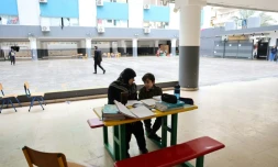 Une femme, assise à cÎté d'un enfant, supervise ses études en ligne sur un téléphone portable dans une école publique transformée en refuge pour personnes déplacées, à Dekwaneh, au nord de Beyrouth, le 25 mars 2026 au Liban
