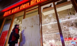 Un homme se tient devant la vitrine brisée d'un supermarché à la suite d'émeutes à Rotterdam, le 25 janvier 2021