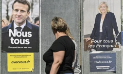 Femme passant deux affiches d'Emmanuel Macron et Marine Le Pen, à Eguisheim (Haut-Rhin), le 21 avril 2022