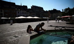 Des personnes se rafraîchissent à une fontaine publique dans une rue de Mulhouse, pendant un épisode de canicule, le 22 août 2023
