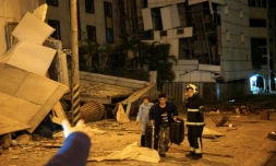 Deux personnes sont escortées par des sauveteurs depuis l'hÎtel Marshal endommagé à Hualien, dans l'est de Taiwan, dans la nuit du 6 au 7 février 2018, aprÚs un violent séisme qui a frappé l'ßle