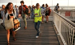 Une bénévole donne des instructions aux vacanciers de LÚge-Cap-Ferret à leur arrivée à Arcachon par bateau, lors d'une opération d'évacuation de l'ensemble de la presqu'ßle du Cap-Ferret, dans le sud-ouest de la France, le 24 juillet 2026