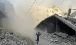 Un garçon palestinien fuit en courant des frappes aériennes à Jabalia, dans le nord de la bande de Gaza, le 19 août 2025

