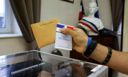 Un électeur tient une carte électorale et un bulletin de vote avant de voter dans un bureau de vote à Etaples, pour le second tour des élections régionales, le 27 juin 2021