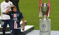 L'attaquant du Paris Saint-Germain Kylian Mbappé enlève sa médaille de finaliste en passant à côté du trophée de vainqueur de la Ligue des champions après la défaite en finale contre le Bayern Munich le 23 août 2020 à Lisbonne