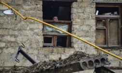Un vieil homme regarde par une fenêtre endommagée par une explosion à Stepanakert au Nagorny Karabakh le 6 octobre 2020