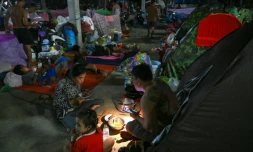 Une famille déplacée par les combats prend un repas en s'éclairant avec une lambe de poche dans un camp de la province de Banteay Meanchey, au Cambodge, le 12 décembre 2025
