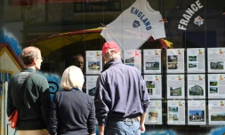 Des badauds regardent la devanture d'une agence immobiliĂšre s'adressant particuliĂšrement aux acheteurs britanniques Ă Eymet (Dordogne) le 16 juin 2016