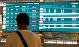 Un passager bloqué à l'aéroport international Soekarno-Hatta en raison de l'éruption du volcan Anak Krakatau, regarde un écran d'information sur les vols, le 7 septembre 2026 à Tangerang, en Indonésie