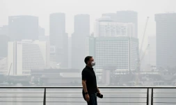 Un passant porte un masque de protection le long du boulevard Ă Marina Bay, noyĂ© dans la brume, le 12 octobre 2026 Ă SingapourÂ