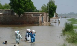 Des personnes touchées par les inondations traversent une zone submergée par les eaux de mousson, des sacs d'aide alimentaire sur le dos dans les faubourgs de Jacobabad, au Pakistan, le 6 septembre 2022