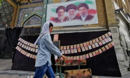 Une passante marche à côté des portraits des trois guides suprêmes de l'histoire de la République islamique d'Iran, l'ayatollah Rouhollah Khomeini, l'ayatollah Ali Khamenei et Mojtaba Khamenei (de gauche à droite), et de photos d'enfants tués lors du bombardement de l'école de Minab en février, le 25 avril 2026 à Téhéran