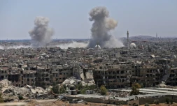 Photo prise le 24 avril 2018 lors d'un voyage de presse organisé par le gouvernement montrant de la fumée s'élevant de bùtiments dans le camp de réfugiés palestiniens de Yarmouk, prÚs de Damas, lors de bombardements visant le groupe Etat islamique (EI)