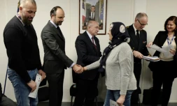 Edouard Philippe et le ministre de l'Intérieur Gérard Collomb (C) serrent la main de réfugiés à Lyon, le 19 février 2018