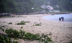 Des personnes se promènent sur une plage jonchée de débris laissés par le typhon Noul, à Hong Kong, le 26 juillet 2026