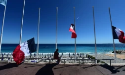 Une femme entre des drapeaux français en bernes à Nice, le 15 juillet 2016