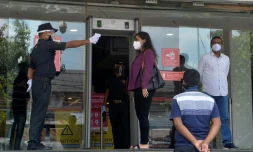 Un agent de sécurité prend la température d'une femme avant qu'elle entre dans un centre commercial, le 8 juin 2020 à Siliguri, en Inde