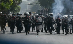 Des policiers courent vers des manifestants rassemblés contre le coup d'Etat militaire, le 27 février 2021 à Rangoun, en Birmanie
