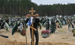 Un employé communal plante une croix sur une tombe pendant un enterrement à Irpin (Ukraine), dont le cimetiÚre compte de nombreuses nouvelles sépultures, le 19 avril 2022