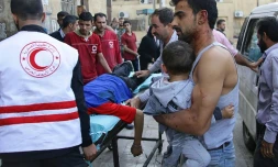 Un Syrien porte un enfant dans ses bras en attendant d'avoir accès à un hôpital le 13 octobre 2016 à Alep en Syrie
