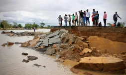 Des habitants debout près d'une route endommagée entre Beira et Chimoio, dans le centre du Mozambique, le 19 mars 2019, après le passage du cyclone Idai