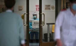 Un membre du personnel médical en combinaison de protection (c) attend de prendre la température des personnes qui arrivent à l'hôpital Princess Margaret, le 4 février 2020 à Hong Kong