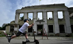 Un enfant passe trottinette devant les ruines de la mairie d'Okhtyrka, le 1er août 2022 en Ukraine 