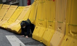 Une habitante de Wuhan, en Chine, épicentre de l'épidémie à ses débuts, passe sous une barricade, le 2 avril 2020   