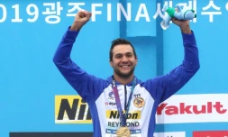 Le Français Axel Reymond bras levés sur le podium aprÚs avoir remporté le 25 km en eau libre aux Mondiaux de natation, le 19 juillet 2019 à Yeosu en Corée du Sud