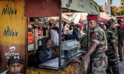 Au lendemain de la prise de pouvoir, un soldat de l'unité Capsat discute avec une vendeuse près de sa base militaire à Antananarivo, le 15 octobre 2025
