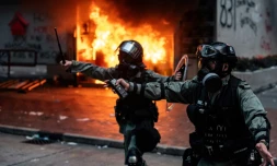Policiers hongkongais devant un immeuble dont l'entrée est feu, aprÚs des heurts avec des manifestants, le 29 septembre 2019