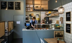 Kajetan Grzelczak derrière son comptoir  au café Andon à Stockholm, entièrement dirigé par l'IA, le 27 avril 2026