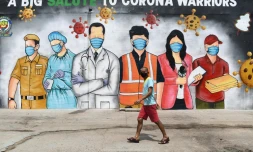 Un homme passe dant une fresque murale qui rend hommage aux "guerriers du corona", le 31 mai Ă New Delhi