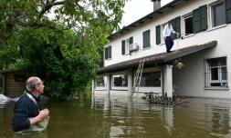 Un homme se sert d'une corde et d'une échelle pour sortir de sa maison inondée, le 20 mai 2023 à Ghibullo, près de Ravenne, en Italie