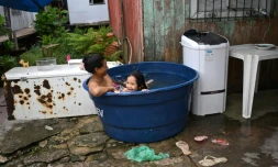 Une femme et sa fille se rafraĂźchissent dans une grande bassine remplie d'eau Ă Vila da Barca, un quartier pauvre bĂąti sur pilotis sur les rives du fleuve Guama Ă Belem, dans l'Ătat du Para, le 5 novembre 2025 au BrĂ©sil